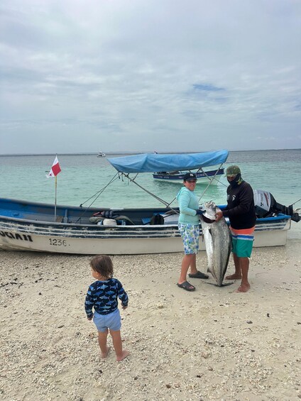 A beach scene with a boat, a flag, and people. 4