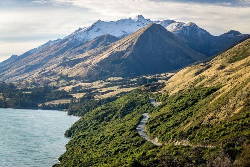 Un paisaje montañoso con una carretera serpenteante, un lago y picos nevados. 5