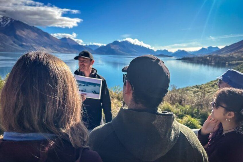Un grupo de personas observando un paisaje con montañas y un lago. 4
