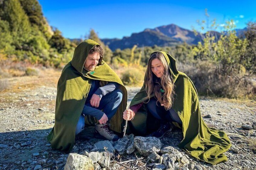 Dos personas sentadas sobre una superficie rocosa con un paisaje montañoso al fondo. 1