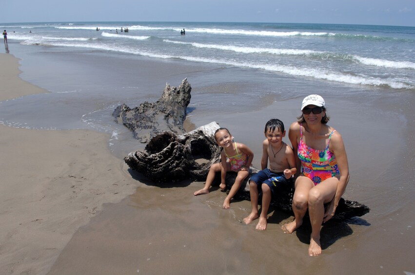 Una playa con una gran formación rocosa, gente en el agua y un cielo despejado. 4