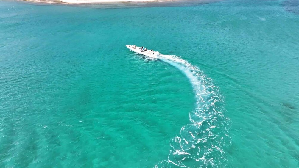 A white boat creating a wake in turquoise water. 2
