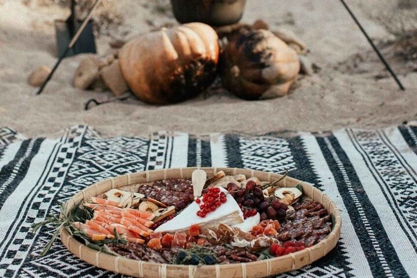 A charcuterie board with various meats, cheeses, and fruits on a woven mat. 3
