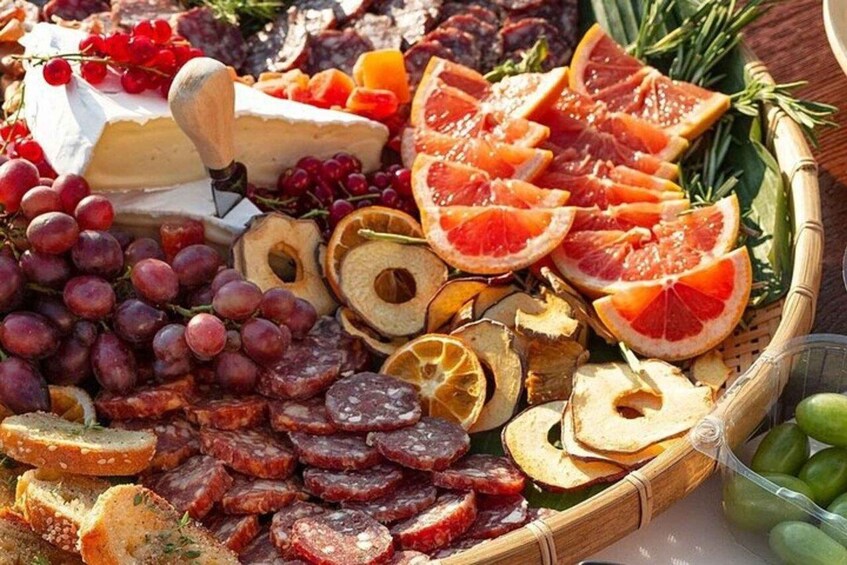 A charcuterie board with cheese, grapes, sliced oranges, dried fruits, and various meats. 5