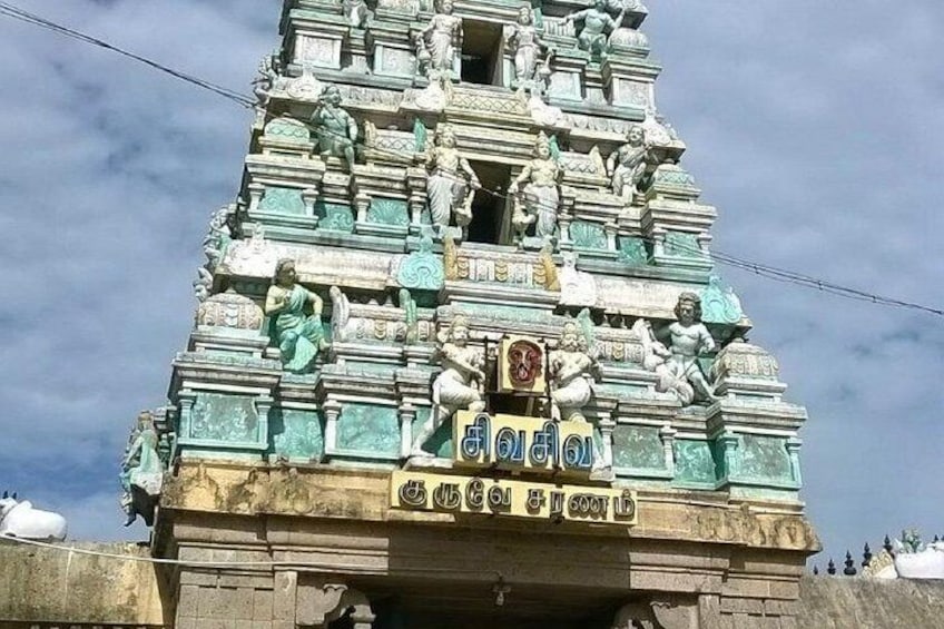 A temple with intricate carvings and a sign in Tamil. 1