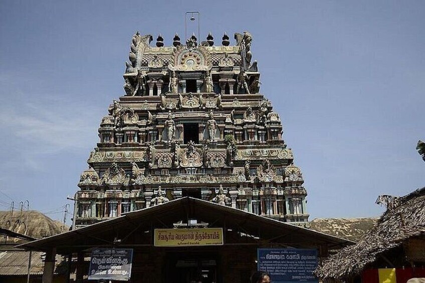 A temple with intricate carvings and a thatched-roof structure in the foreground. 5