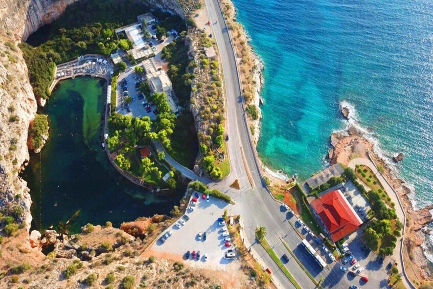 An aerial view of a coastal area with a parking lot, a road, a building with a red roof, and a body of water. 3