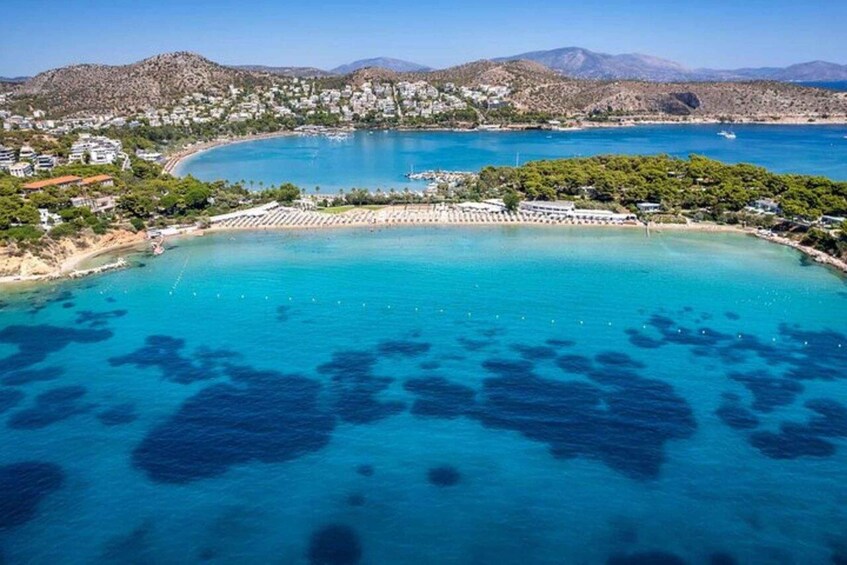 A coastal town with clear turquoise waters, a marina, and mountainous terrain in the background. 4