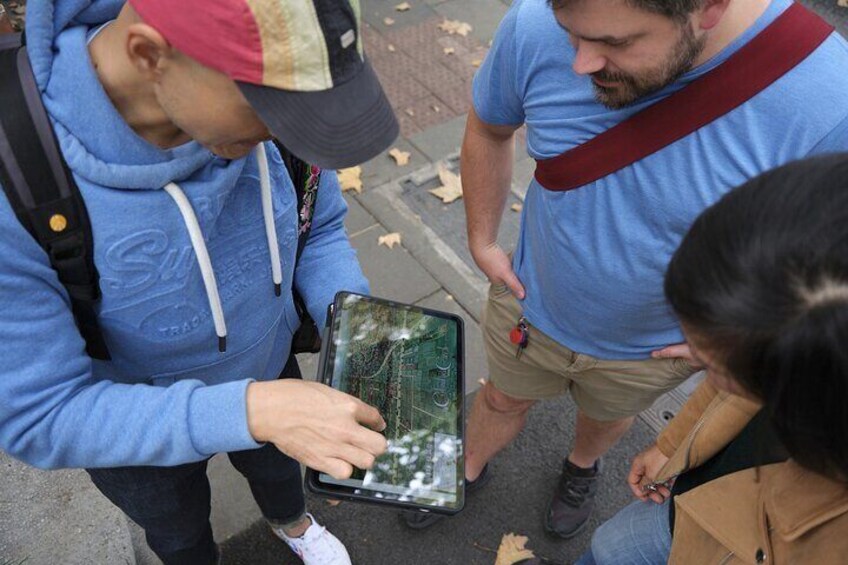 Una persona tiene un tablet che mostra una mappa, un'altra persona indossa un bracciale rosso e una terza persona osserva. 4