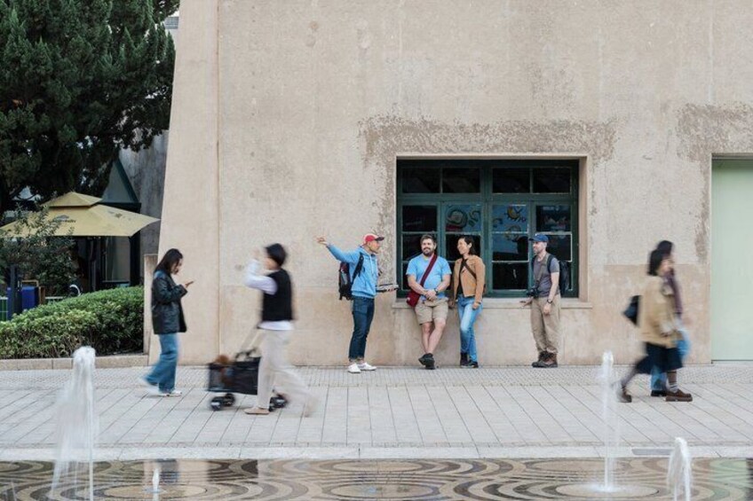 Persone che camminano di fronte a un edificio con una fontana in primo piano. 2