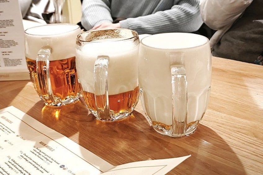 Three beer mugs on a wooden table with a menu in the foreground. 5