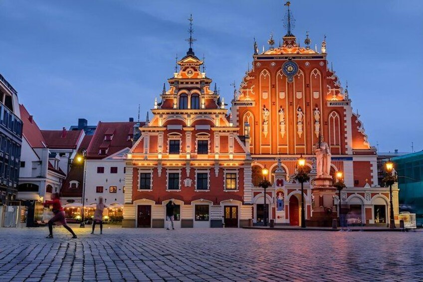 A historic building with ornate architecture, a cobblestone plaza, and a statue in front. 5