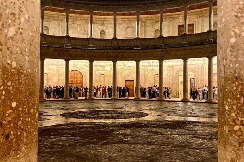 A historic building with a circular courtyard, columns, and a large wooden door. 2