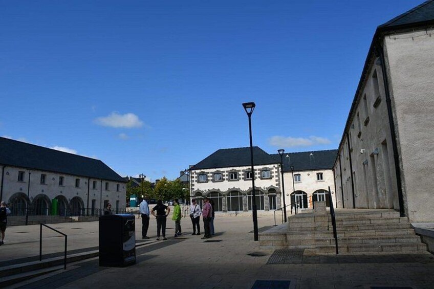 A courtyard with buildings, a street lamp, and people walking. 5