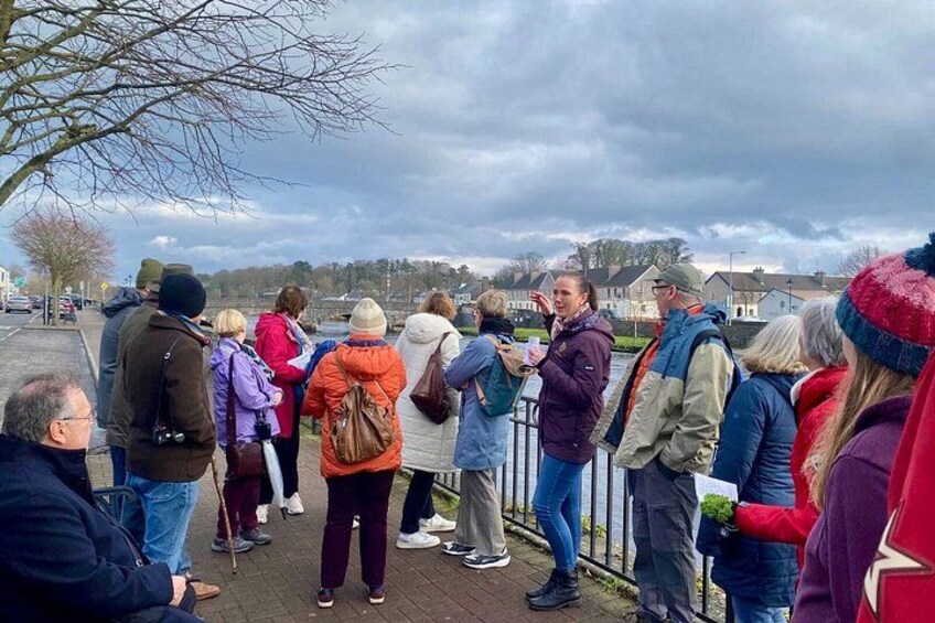 A group of people standing on a bridge, looking out over a body of water. 2