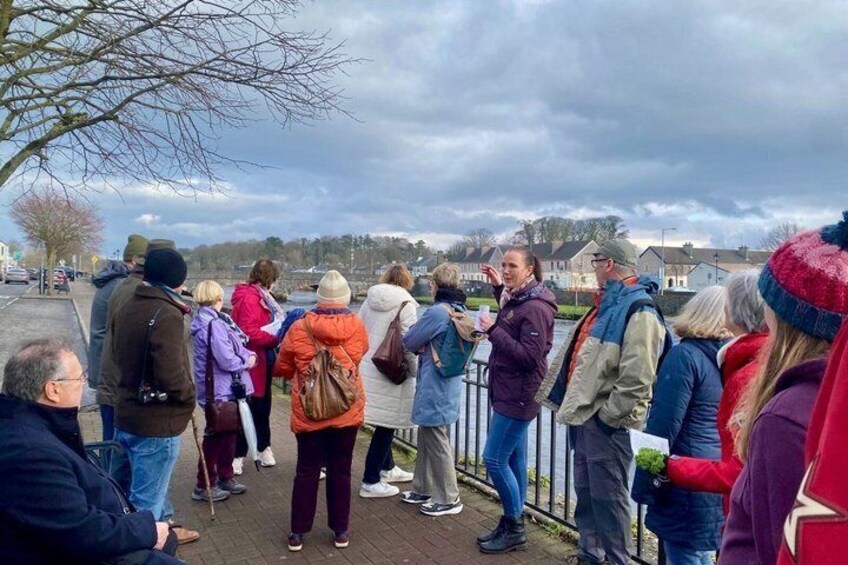 A group of people standing on a bridge, looking at something off-camera. 3