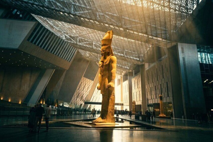 A large golden statue in a modern architectural space with a high ceiling and geometric patterns. 1