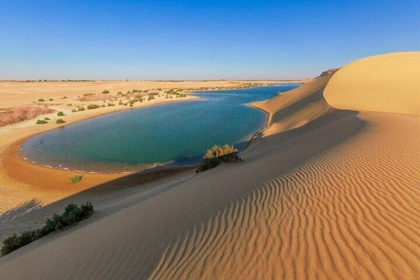 A desert landscape with sand dunes and a body of water. 5
