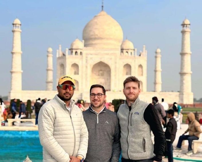Three people standing in front of the Taj Mahal. 5