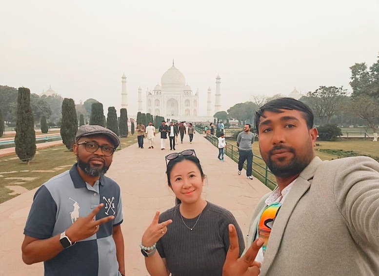 Three people posing in front of the Taj Mahal with a crowd in the background. 4