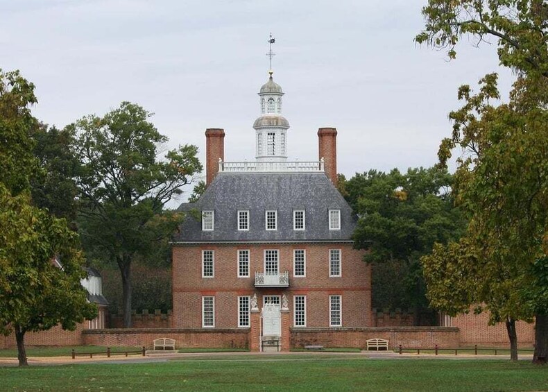 A large brick building with a central tower, surrounded by trees and a grassy lawn. 1
