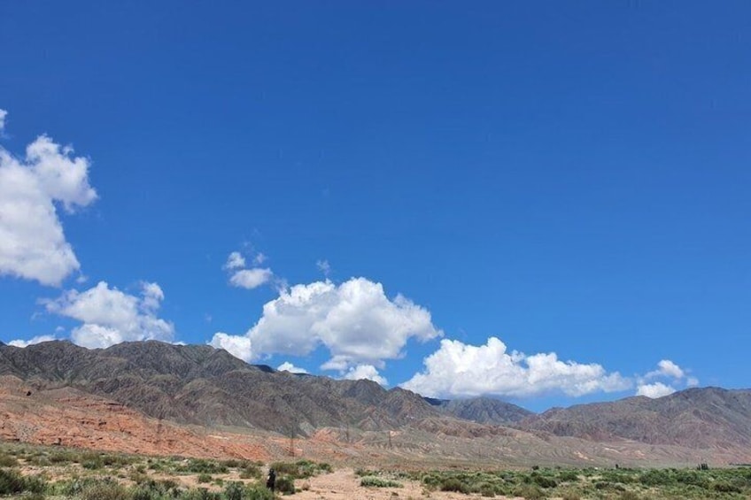 A desert landscape with mountains, sparse vegetation, and a clear blue sky. 4
