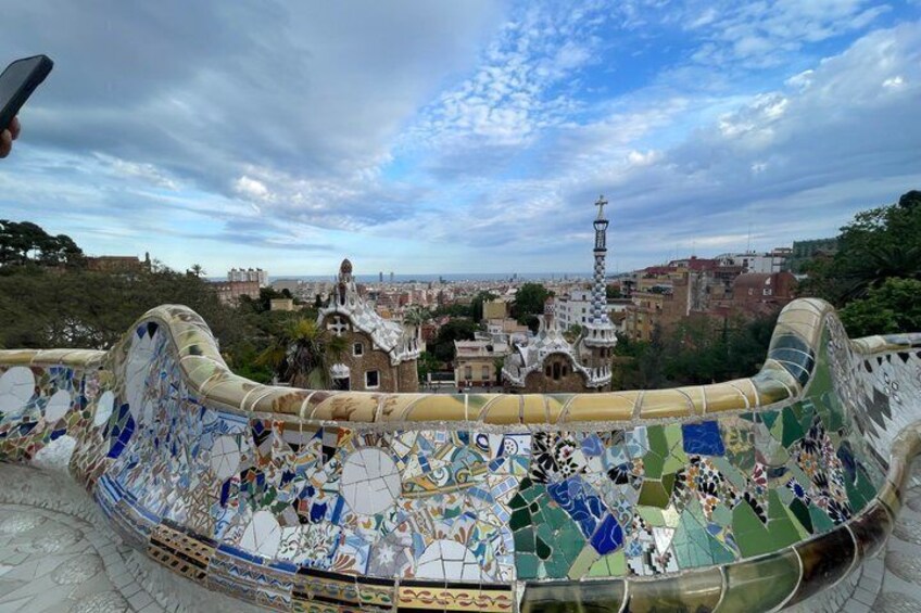 A mosaic-adorned terrace with a view of a tower and buildings in the distance. 5
