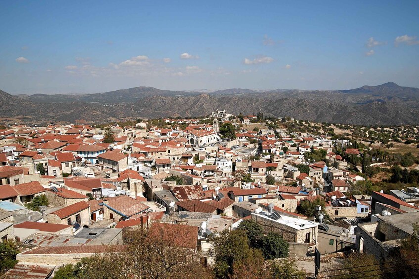 A town with red-roofed buildings, a prominent church, and mountains in the background. 4