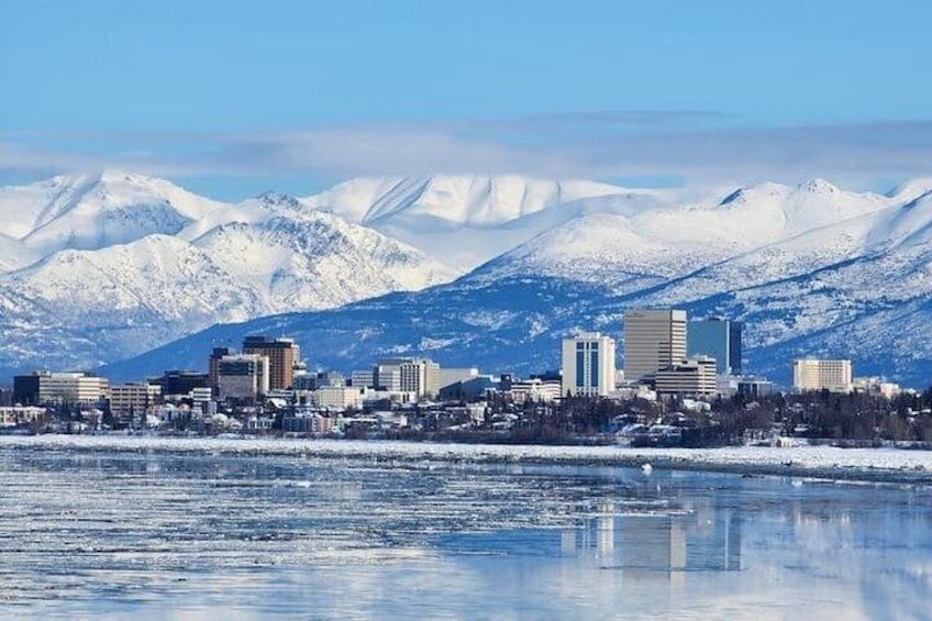 Une vue urbaine avec, en arrière-plan, des montagnes enneigées et, au premier plan, une étendue d’eau gelée. 2