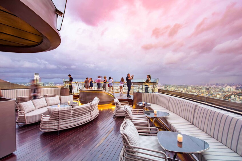 A rooftop lounge with seating and tables, overlooking a cityscape. 5