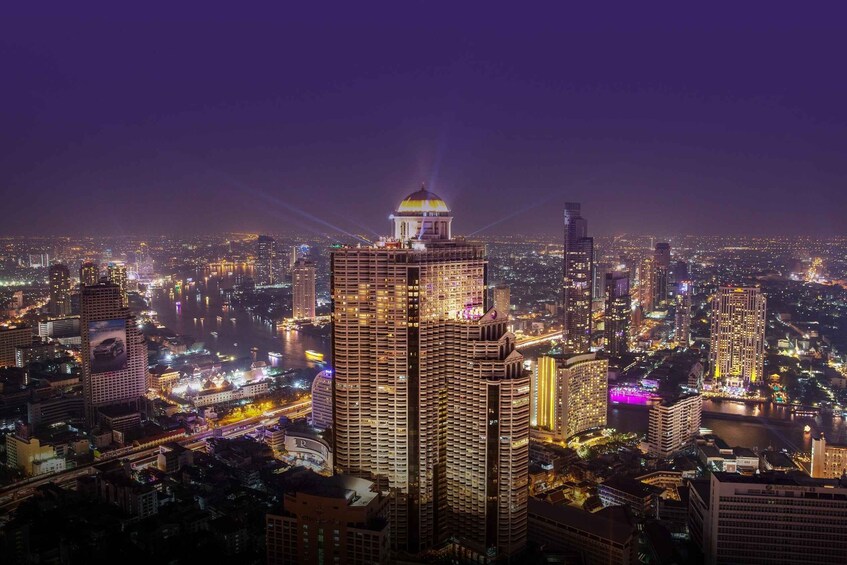 A nighttime cityscape with illuminated buildings and a prominent tower with a dome. 1
