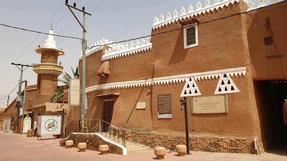 A traditional building with a white-tiled roof, a minaret, and a staircase leading to the entrance. 5