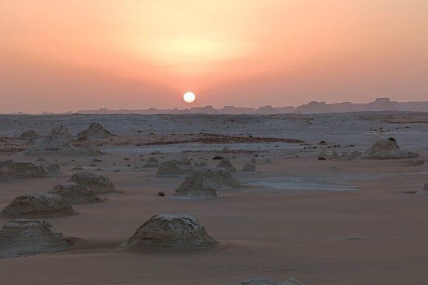 Un paysage désertique avec des dunes de sable et un soleil couchant. 3