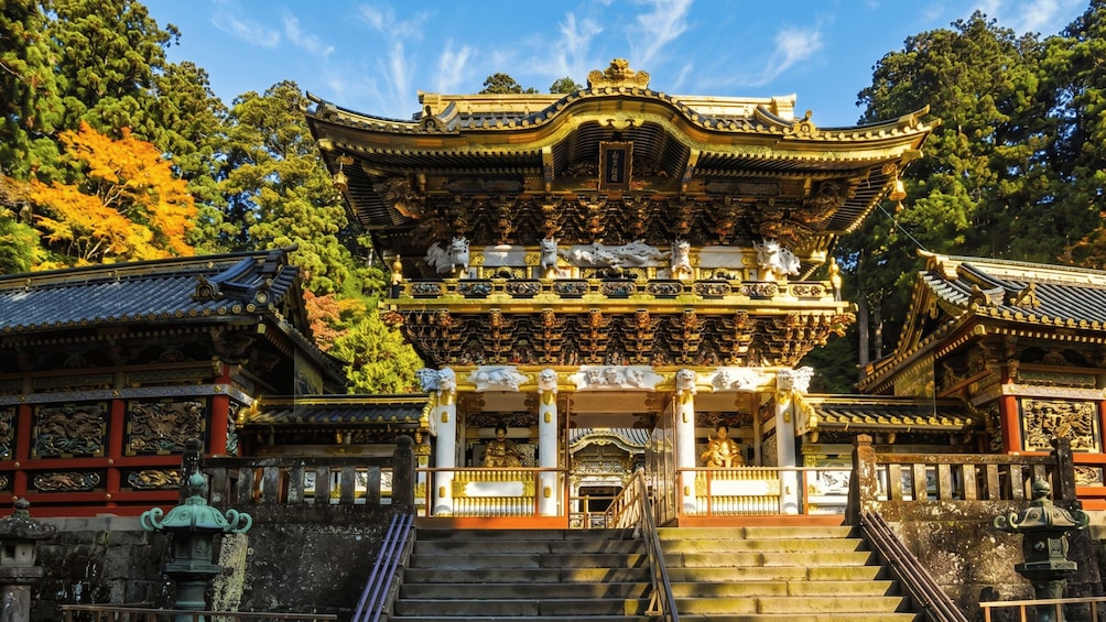 A traditional multi-tiered pagoda with ornate golden decorations and statues, surrounded by lush trees. 3