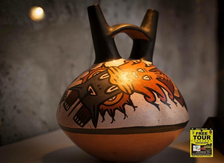 A ceramic vase with a handle and painted designs. 4