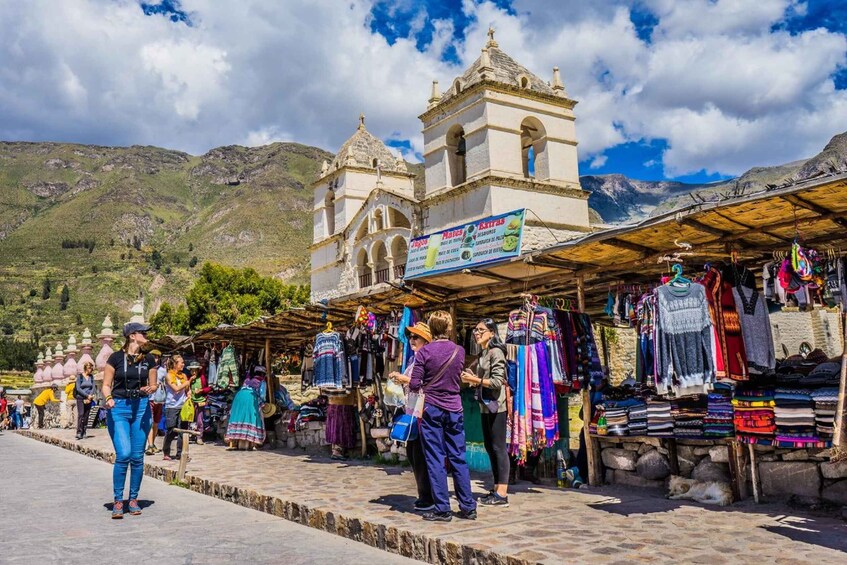 A market with colorful textiles and a historic church in the background. 2