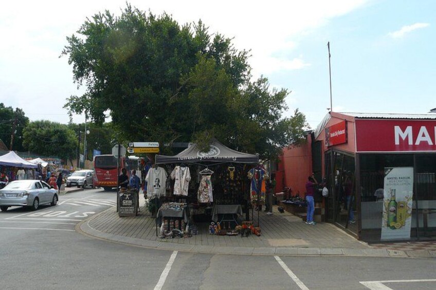 A street market with stalls, a bus, and a building with a red sign. 4