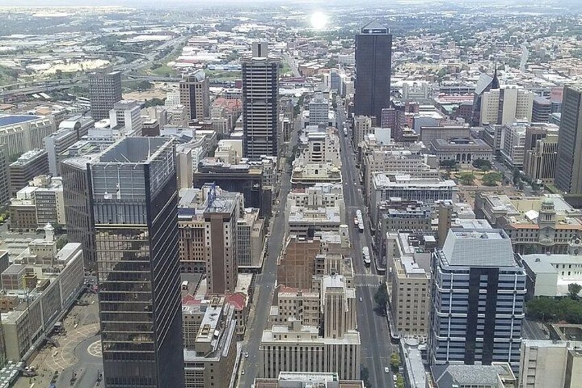 A cityscape with modern high-rise buildings, a central road, and surrounding urban infrastructure. 1