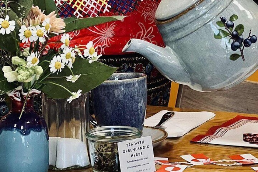 A tea set with a blue teapot, a blue cup, and a glass jar with tea leaves. 4