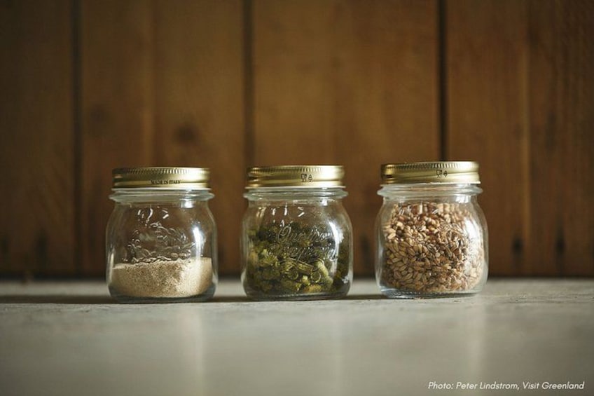 Three glass jars with metal lids containing different grains and seeds on a wooden surface. 2