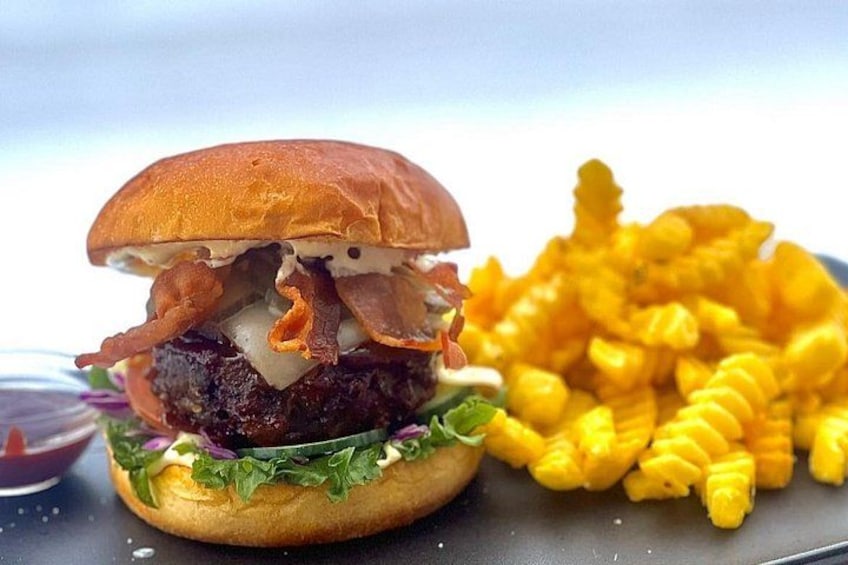 A burger with bacon, lettuce, and a bun, accompanied by a side of French fries. 3