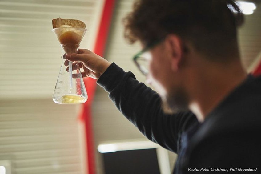 A person holding a measuring flask with a yellow liquid. 4