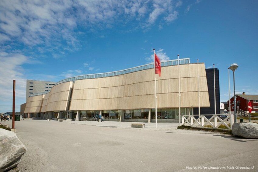 A modern building with a curved facade, a red flag, and a clear sky. 2