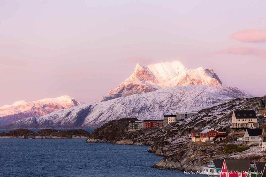 A coastal village with snow-capped mountains in the background. 1