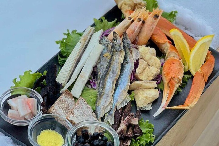 A seafood platter with various fish, crab, and lemon slices on a bed of lettuce. 2