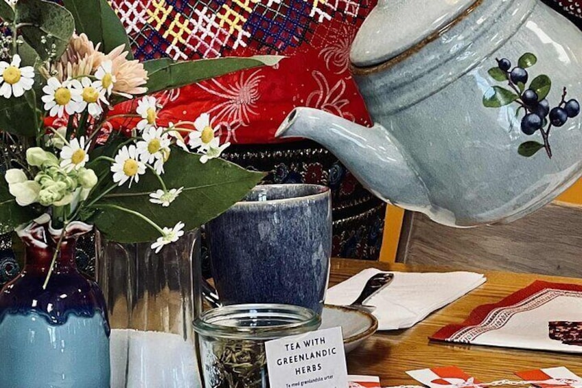 A blue teapot with a floral design, a glass jar with tea, and a label that reads 'Tea with Greenlandic herbs.' 3