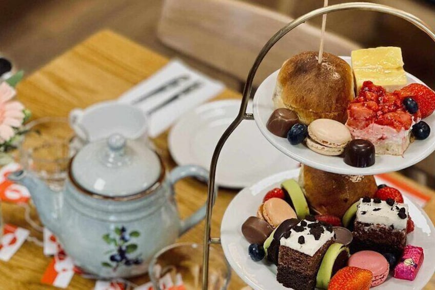 A tiered dessert stand with various pastries and a teapot on a wooden table. 4