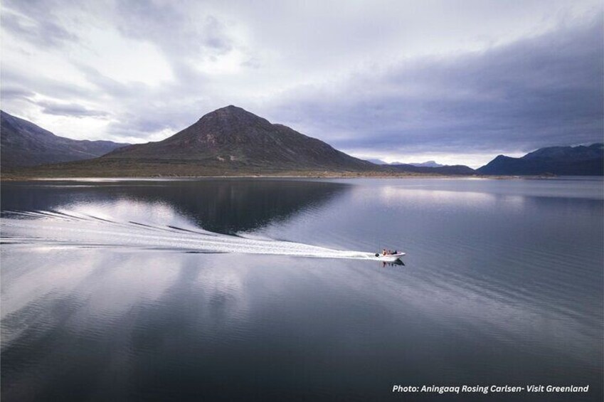 A boat on a calm lake with mountains in the background. 3