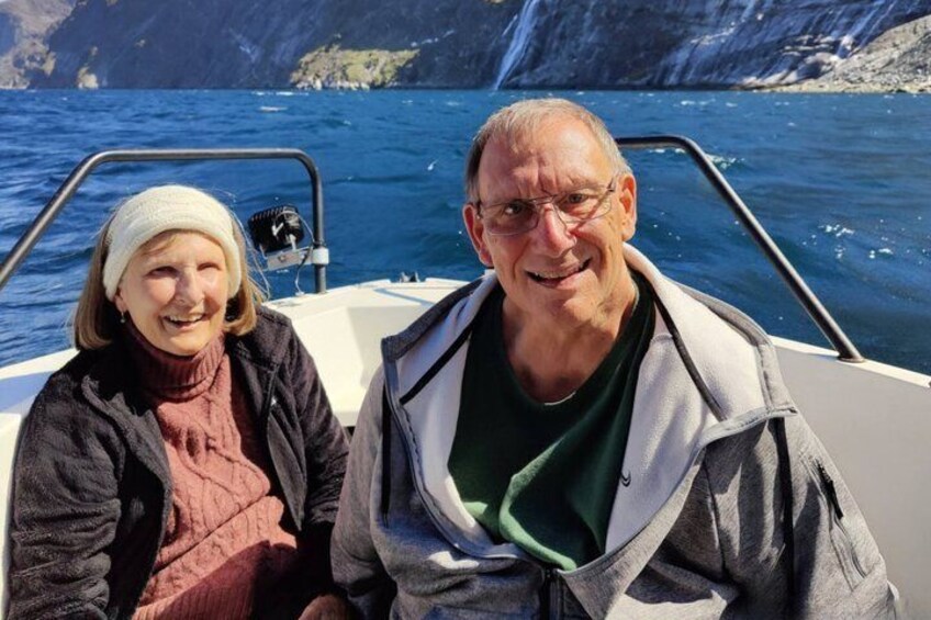 Two people on a boat with a rocky coastline in the background. 2