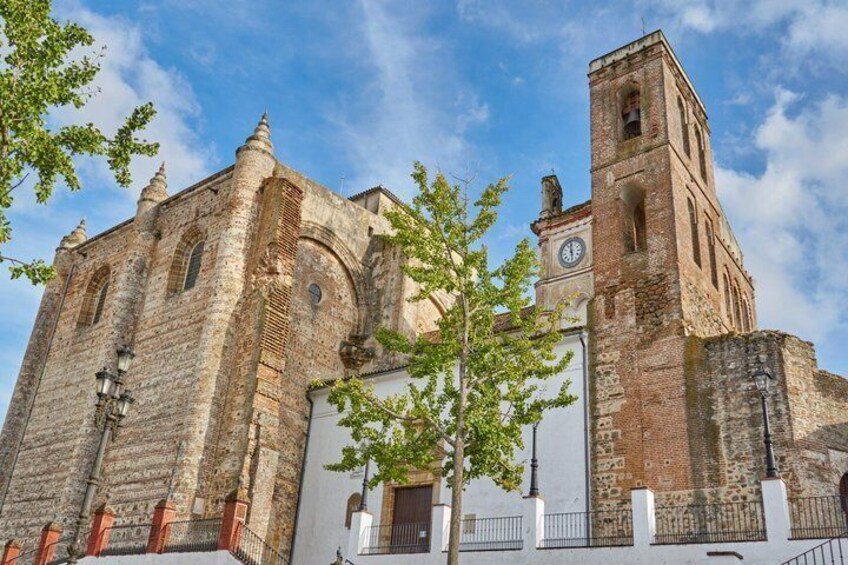 Une église historique dotée d’un clocher, de fenêtres en arc et d’un arbre au premier plan. 1